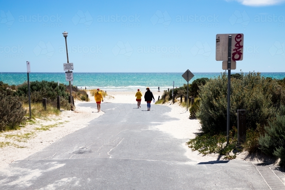 Lifesavers walking down to beach along access road - Australian Stock Image