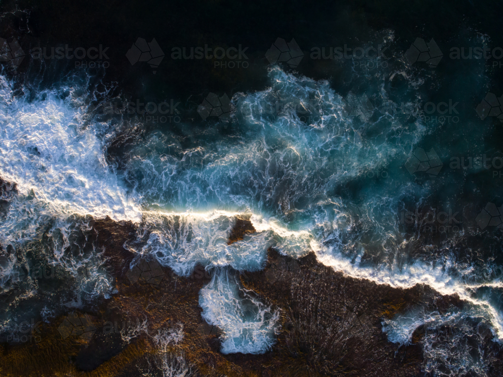 Light captures a breaking wave in the early morning - Australian Stock Image