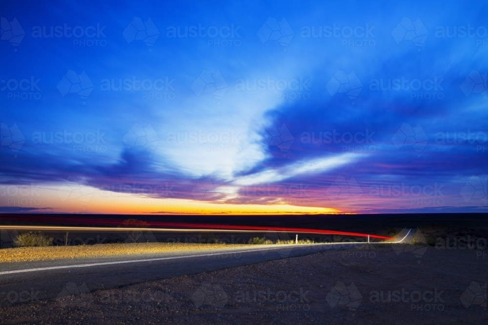 Light trails of a car driving down the road at sunset - Australian Stock Image