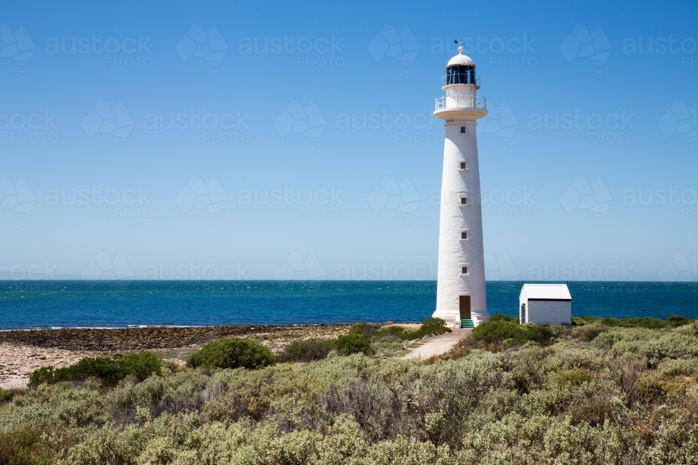 lighthouse with blue water and cloudless sky - Australian Stock Image