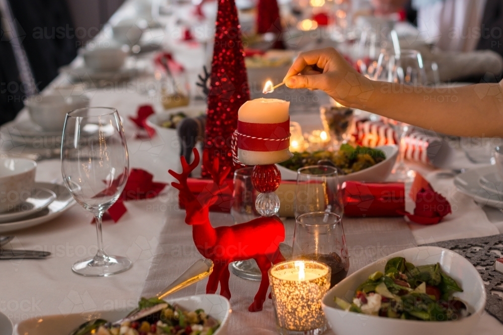 lighting candles on the Christmas dining table - Australian Stock Image