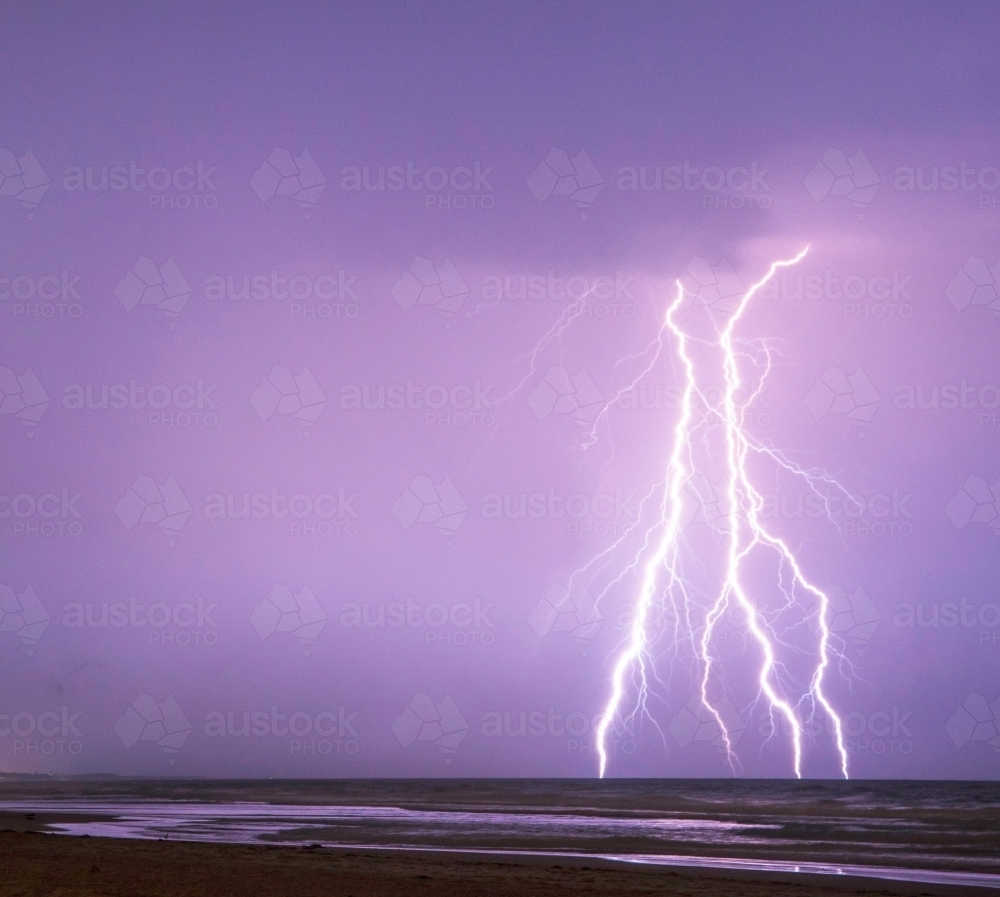 Lightning bolts against the purple night sky over the sea - Australian Stock Image