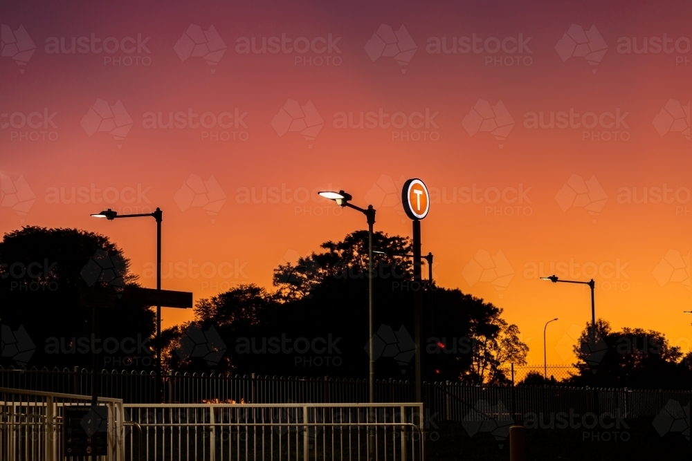 lit up t train station platform sign at dusk in country town - Australian Stock Image