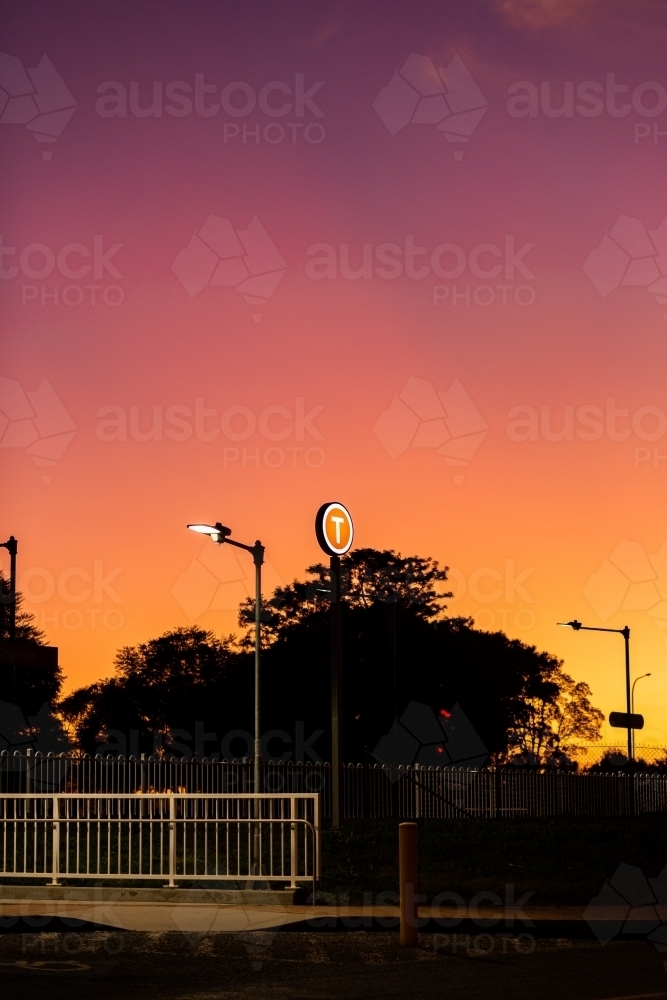 lit up t train station platform sign at dusk in country town - Australian Stock Image