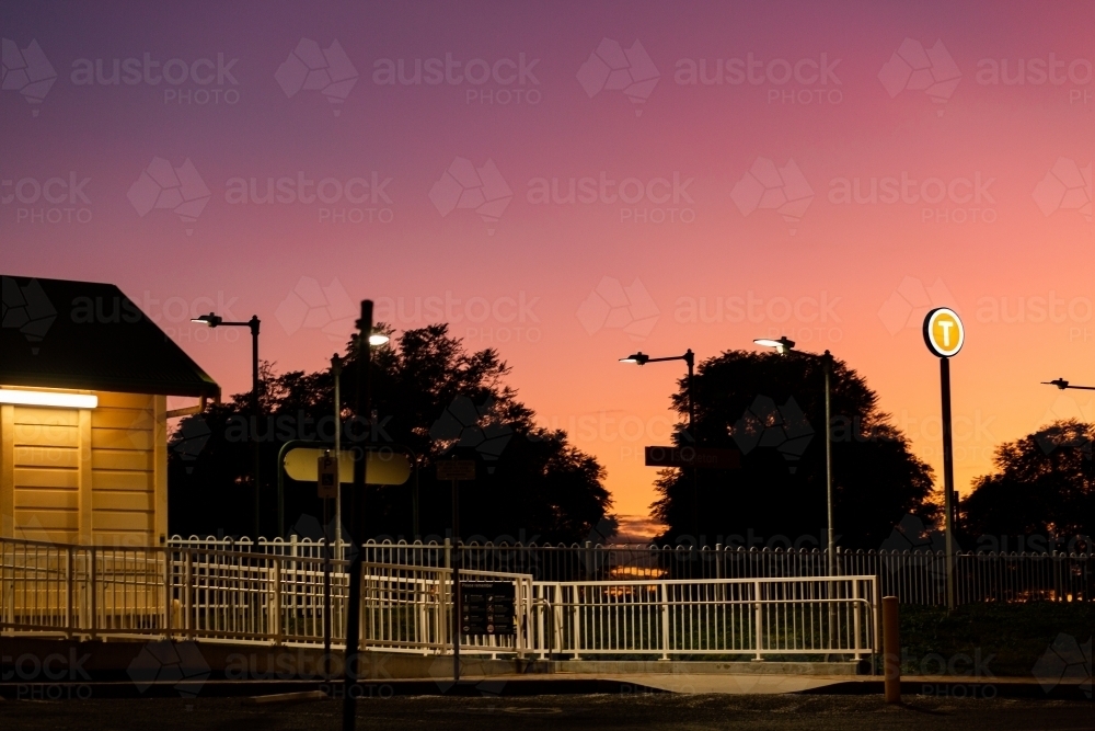 lit up t train station platform sign at dusk in country town - Australian Stock Image