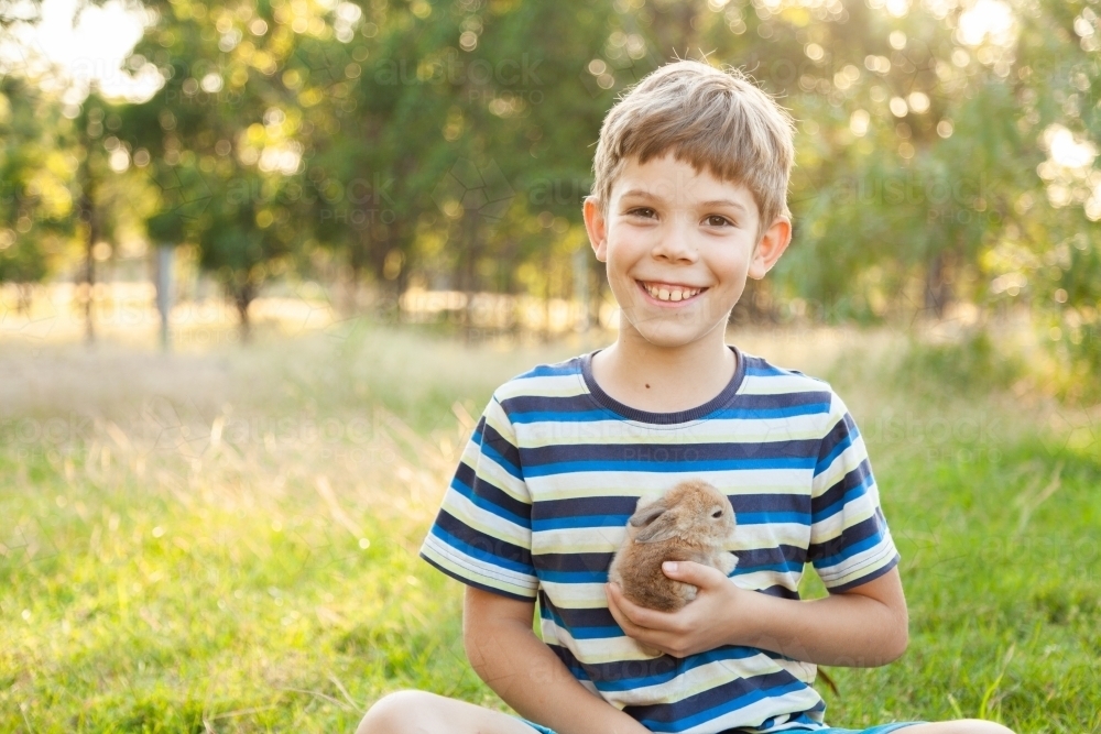 little boy holding his pet a baby bunny rabbit - Australian Stock Image