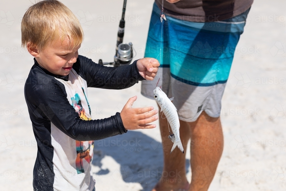 little boy on the beach with his dad and a fish he caught - Australian Stock Image
