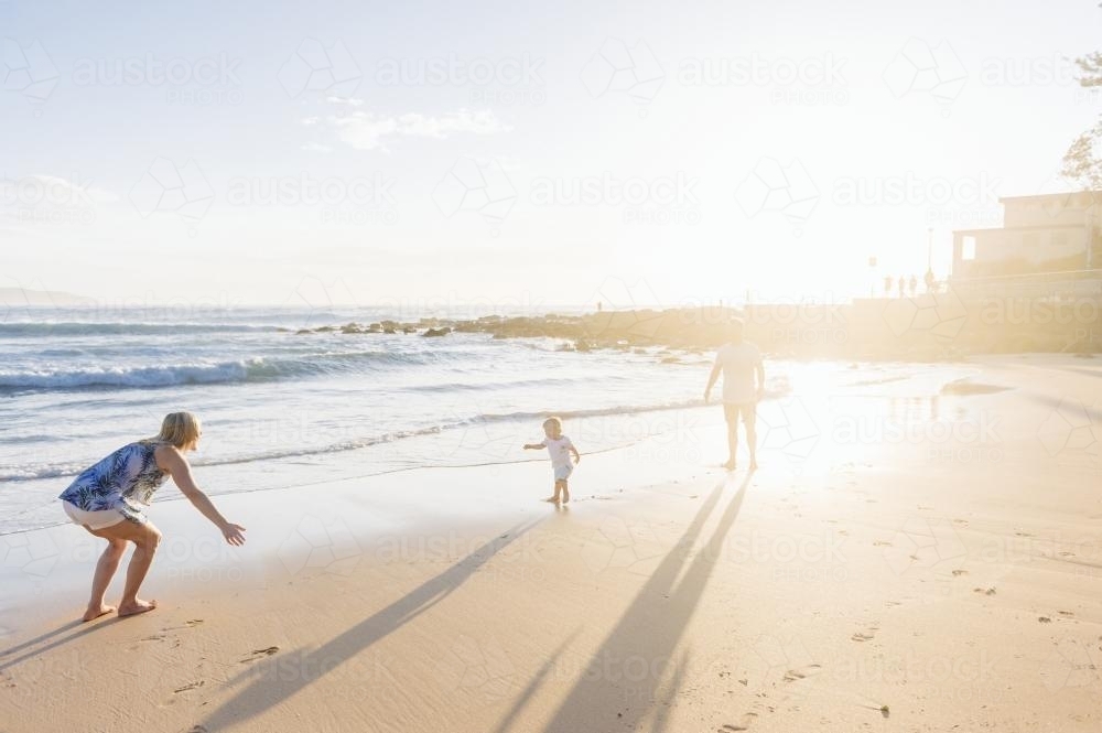 Little boy running to his mum on the beach at sunrise - Australian Stock Image