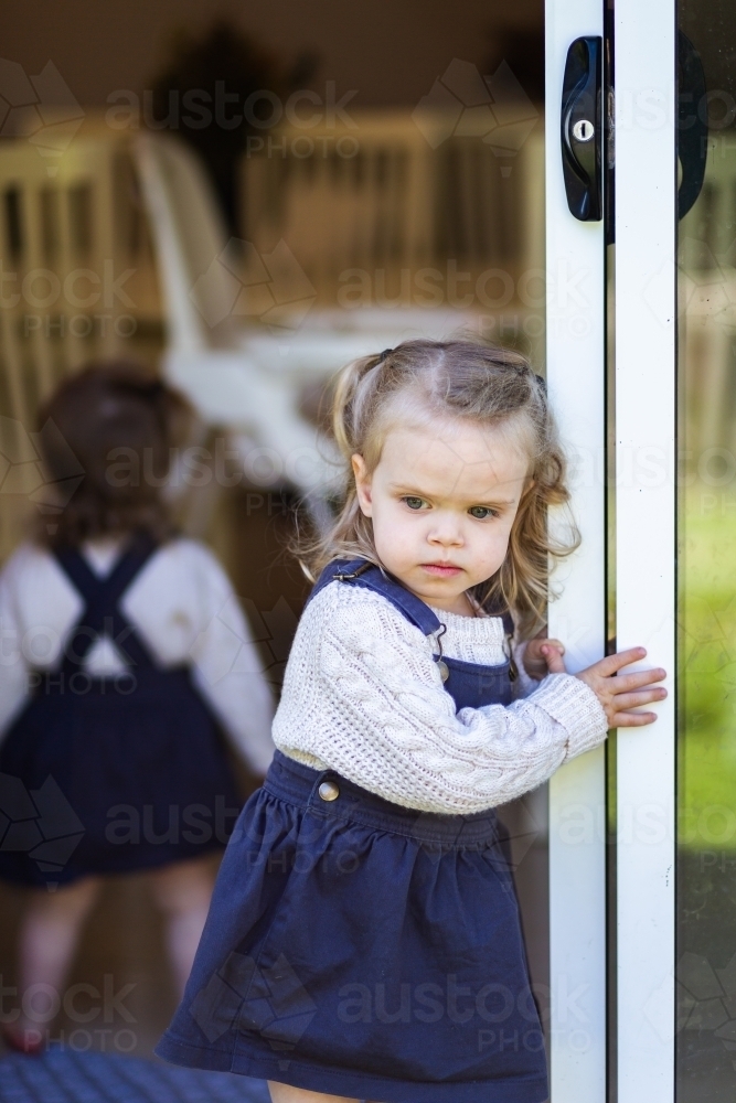 Image of Little girl coming out sliding glass door - Austockphoto