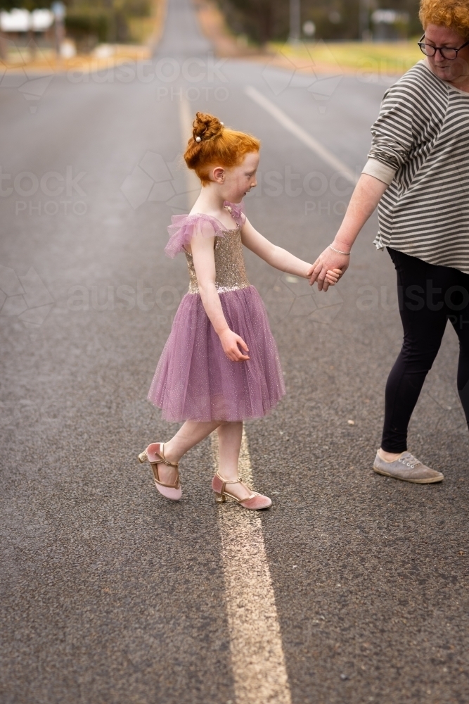 little girl crossing street holding mum's hand - Australian Stock Image