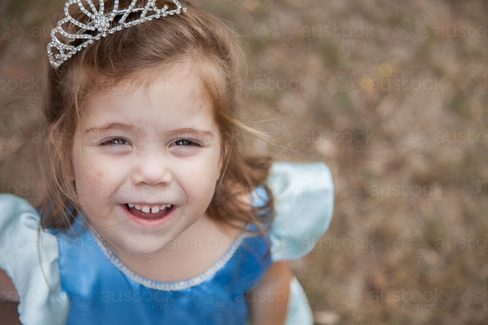 Little girl in princess dress ups costume smiling at camera - Australian Stock Image