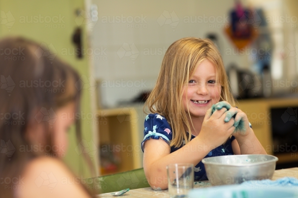 Little girl mixing coloured dough with hands - Australian Stock Image