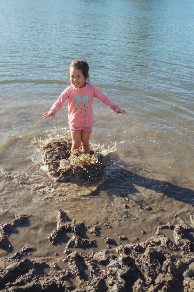 Little girl playing in the muddy beach - Australian Stock Image