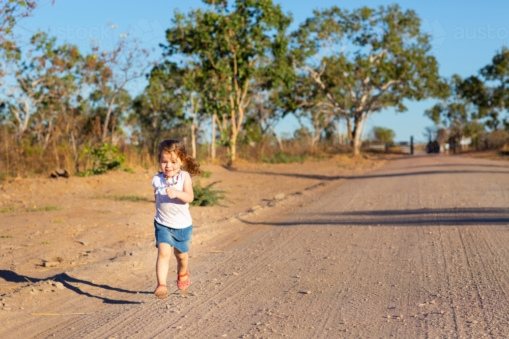 Little girl running down a dirt road - Australian Stock Image