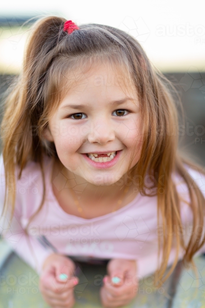 Little girl smiling with front teeth missing - Australian Stock Image