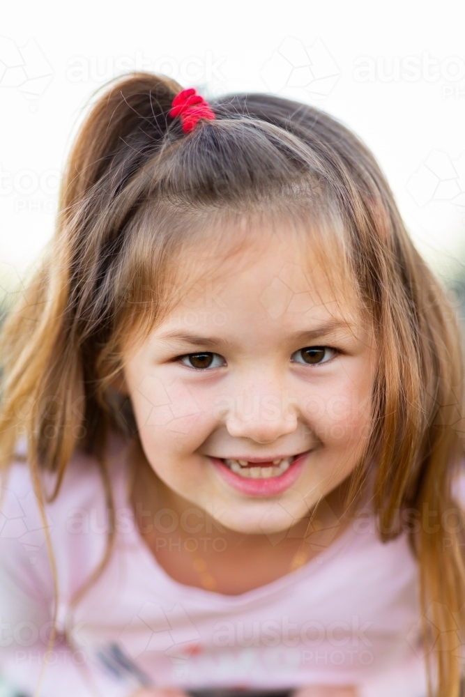 Little girl smiling with front teeth missing - Australian Stock Image