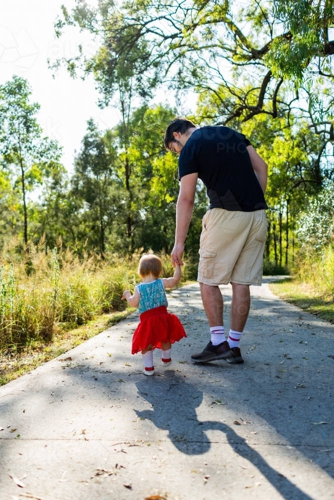 Little girl walking down footpath with dad - Australian Stock Image