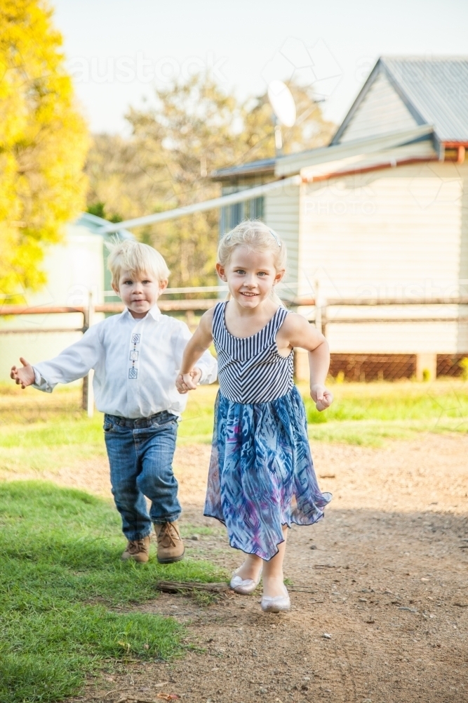 Little kids running around the yard together - Australian Stock Image