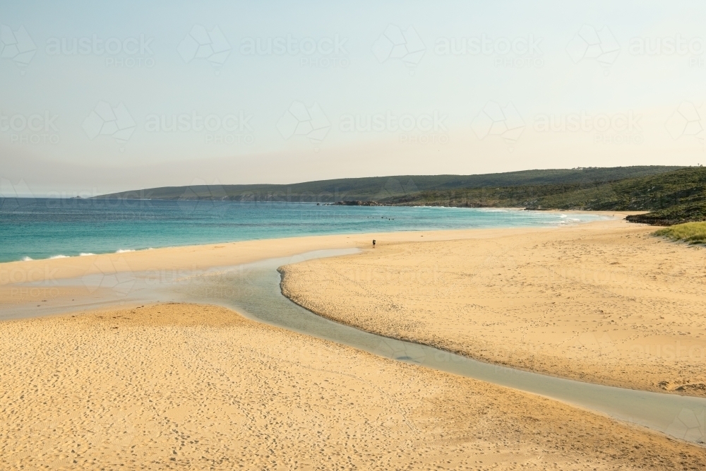 Loan hiker walking on beach with surfers in water - Australian Stock Image