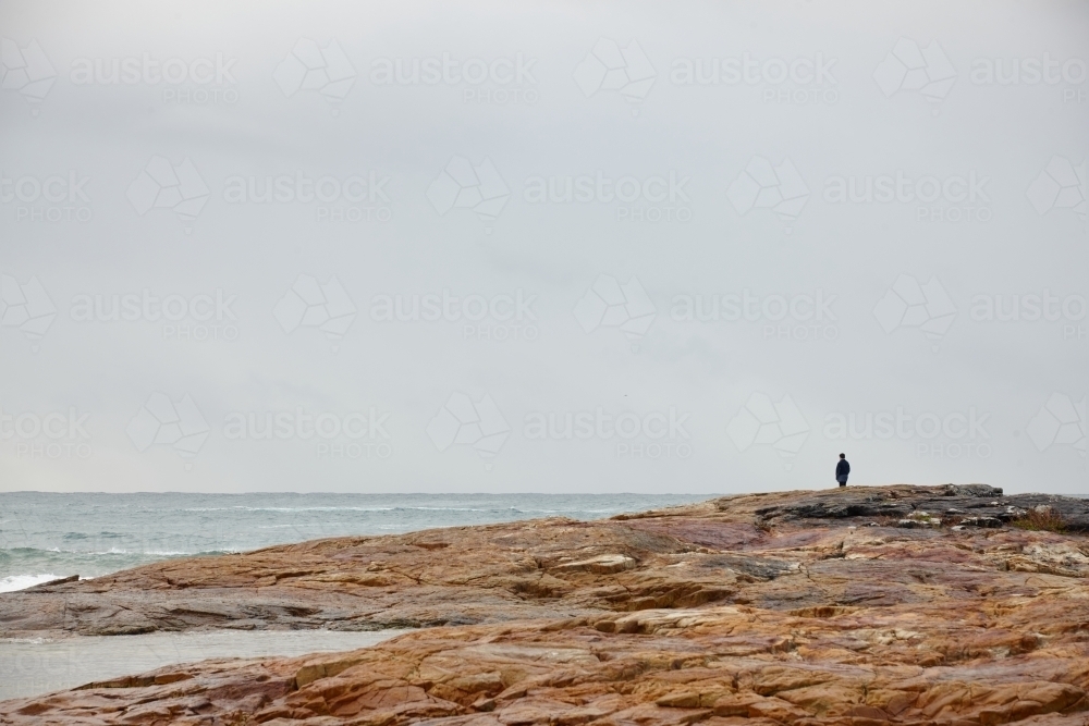 Lone person at coastal landscape on overcast day - Australian Stock Image