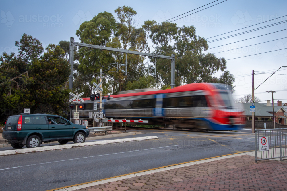 Long exposure of train going across the road at a level crossing - Australian Stock Image