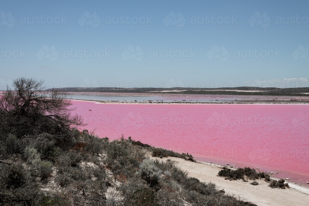 Looking across Pink Lake Lagoon with white sand and low hills in the distance - Australian Stock Image