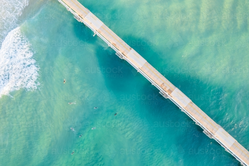 Looking directly down at a jetty with the blue ocean waves on either side - Australian Stock Image