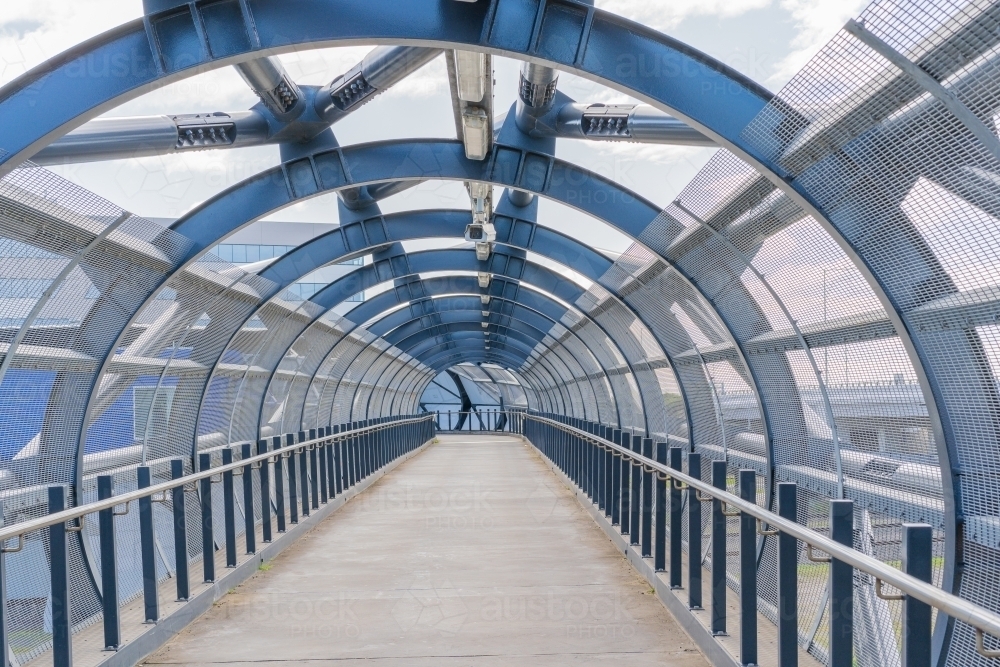 Looking down a tubular metal walkway with steel girders and railings - Australian Stock Image