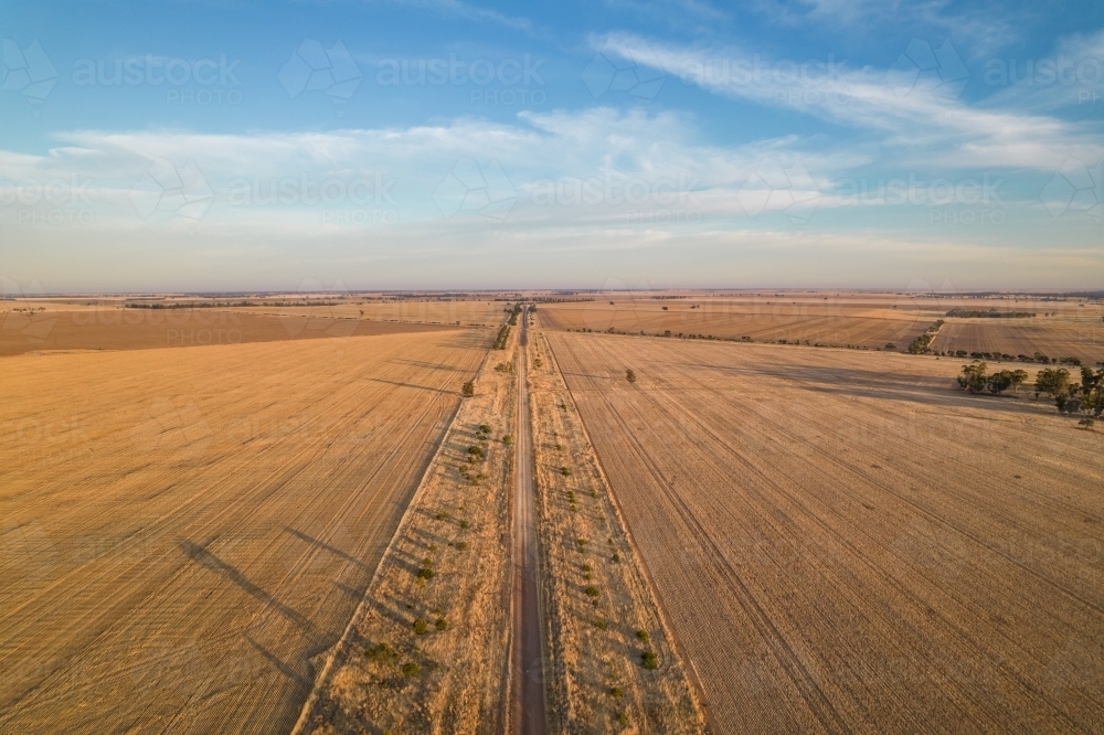 Looking down along a country road through fields in the early morning sunlight - Australian Stock Image