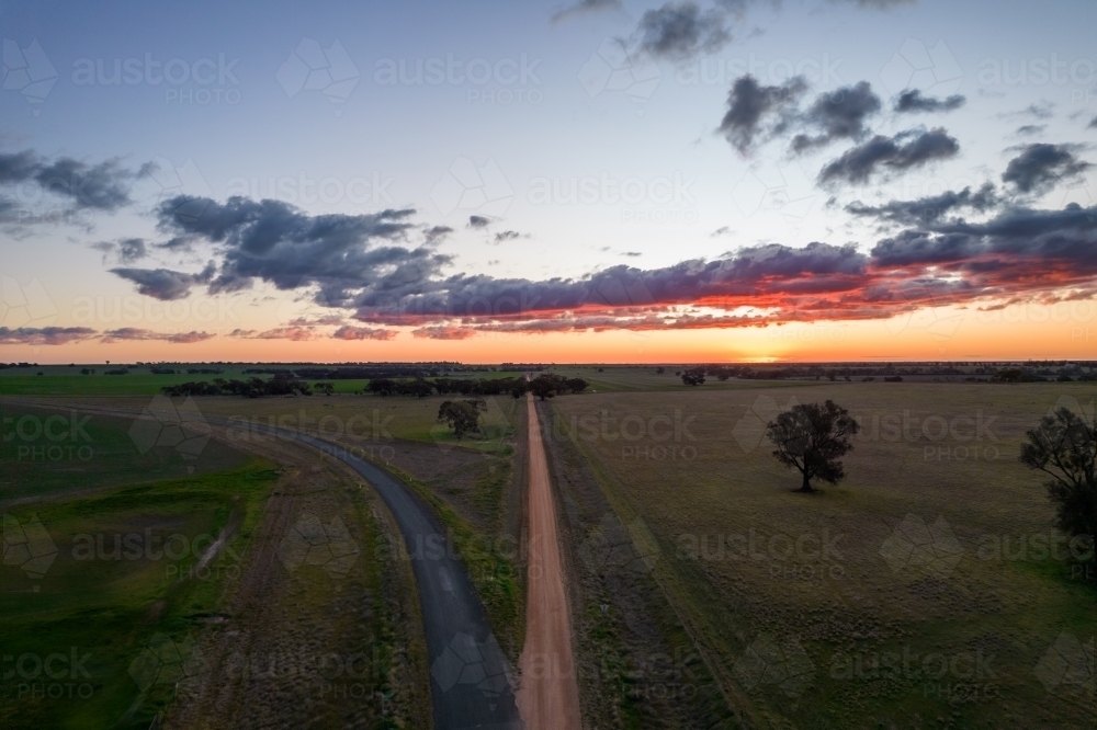 Looking down along the dirt road with the sun setting in the distance. - Australian Stock Image