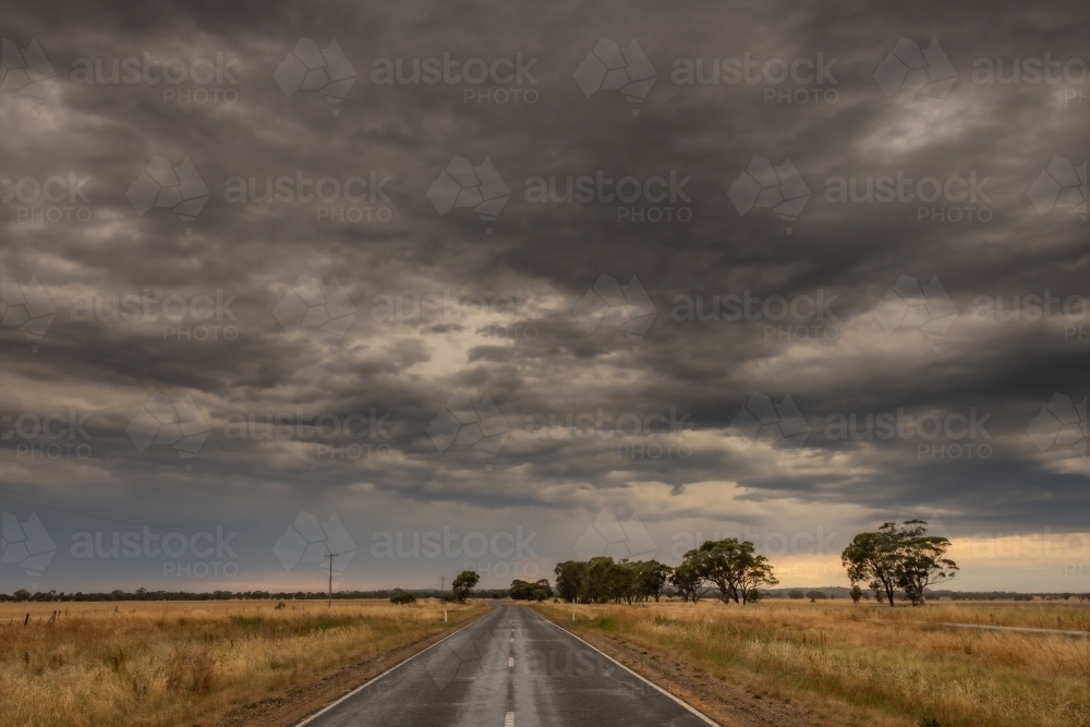 Looking down along the road with the storm clouds approaching. - Australian Stock Image