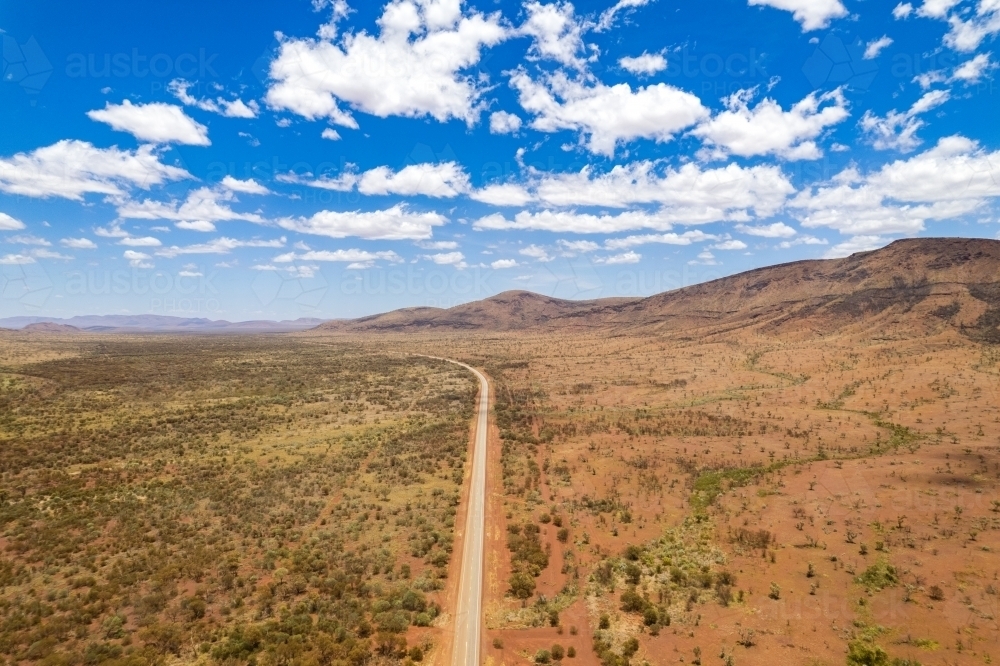 Looking down at asphalt road at the red terrain earth in outback Australia - Australian Stock Image