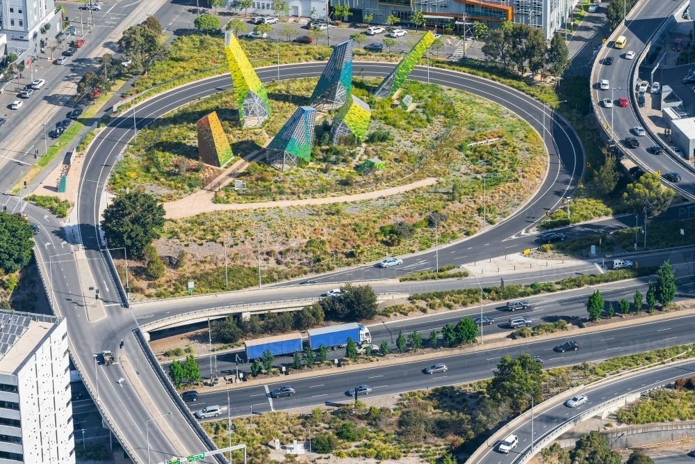 Looking down on a busy freeway with off and on ramps encircling a modern metal sculpture - Australian Stock Image