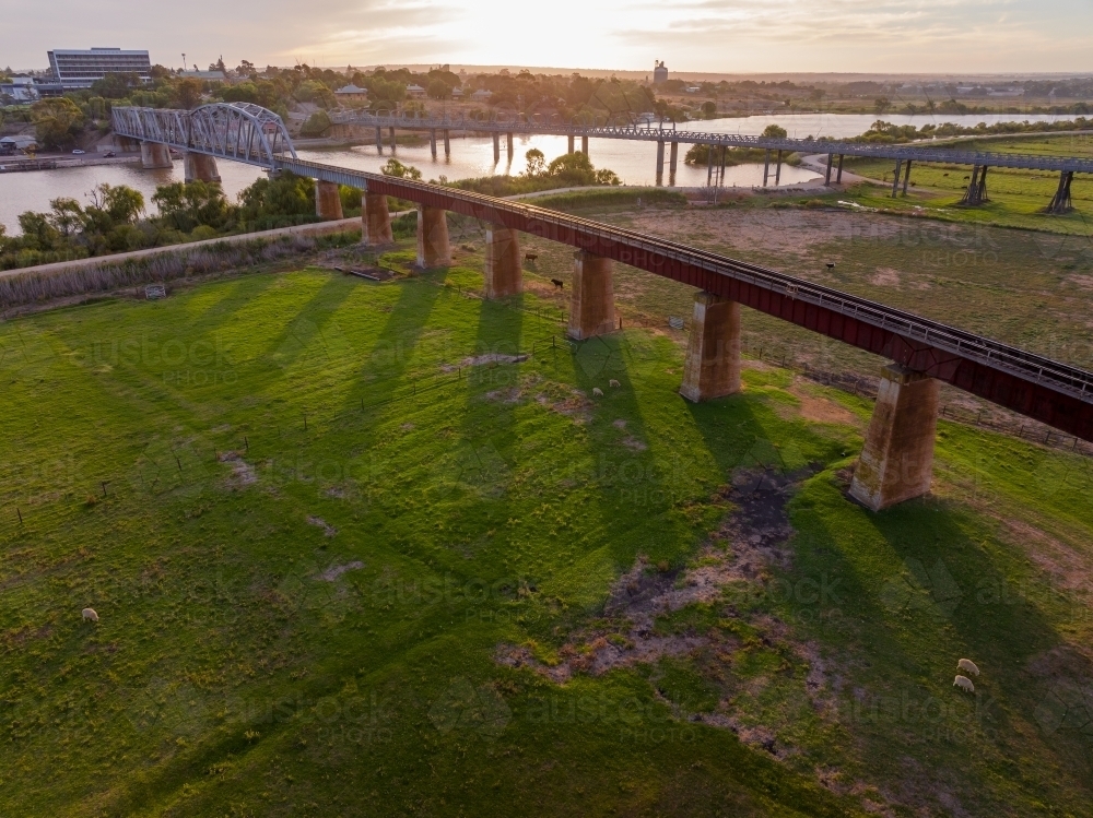 Looking down on a raised railway viaduct over farmland at sunset - Australian Stock Image