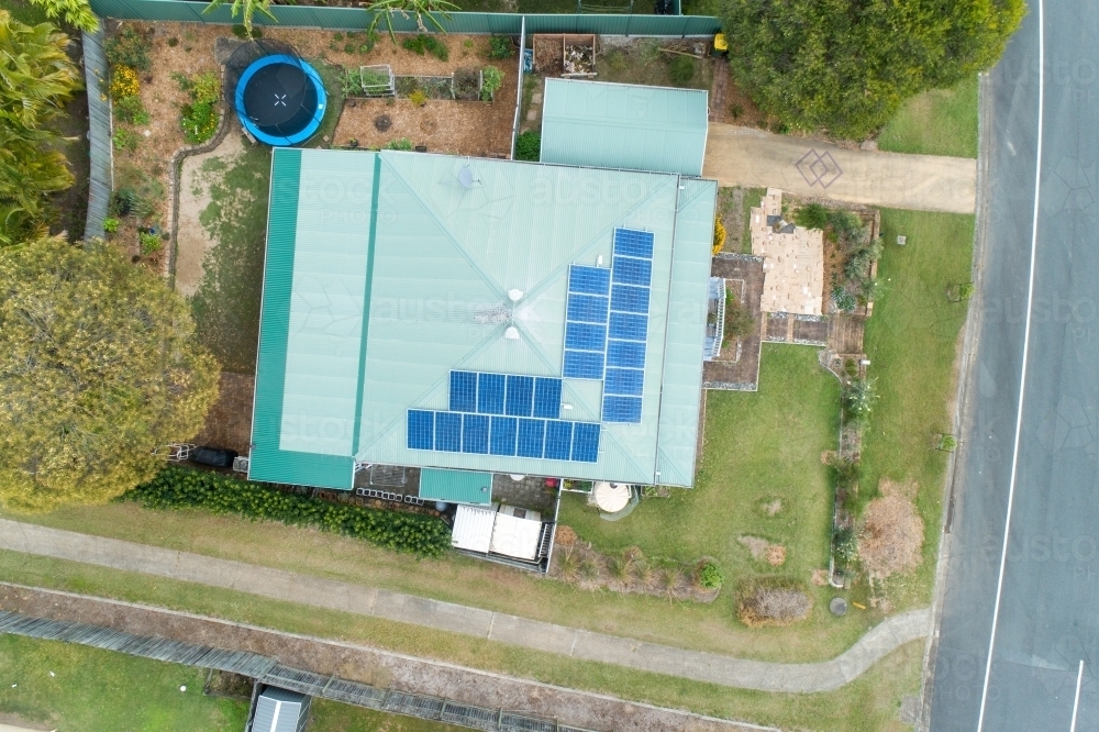 Looking down on house with metal roof and solar panels, and trampoline in back yard. - Australian Stock Image