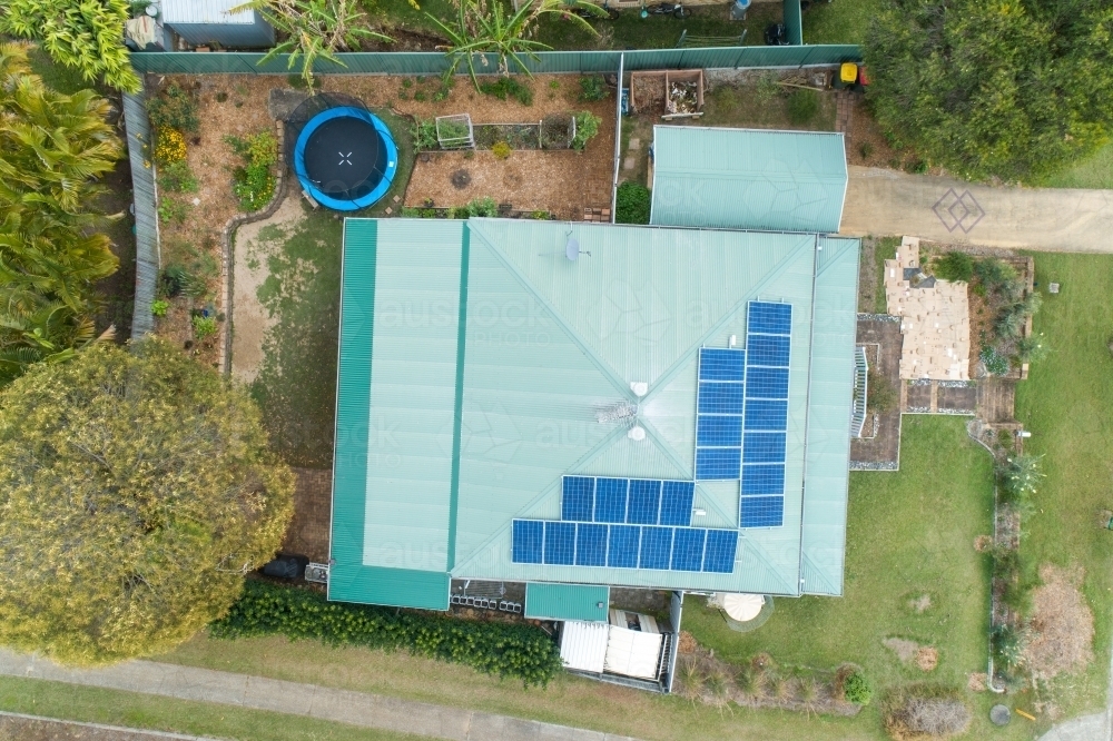 Looking down on house with metal roof and solar panels, and trampoline in back yard. - Australian Stock Image