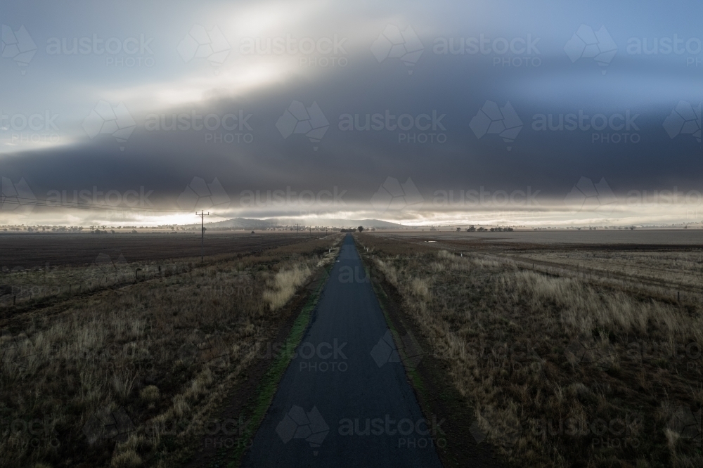 Looking down on the empty countryside road as the storm approaches - Australian Stock Image