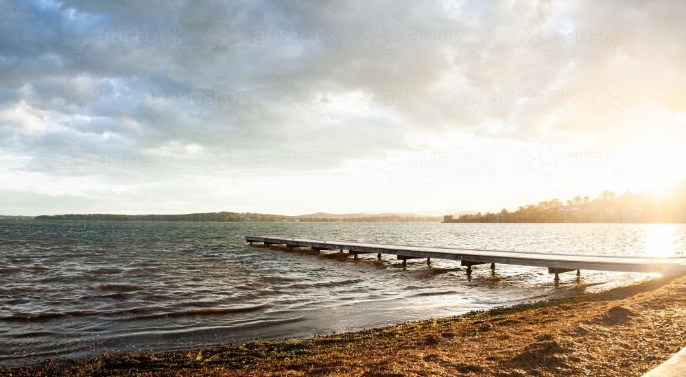 Looking out over jetty and sunlit water of Lake Macquarie at Warners Bay - Australian Stock Image