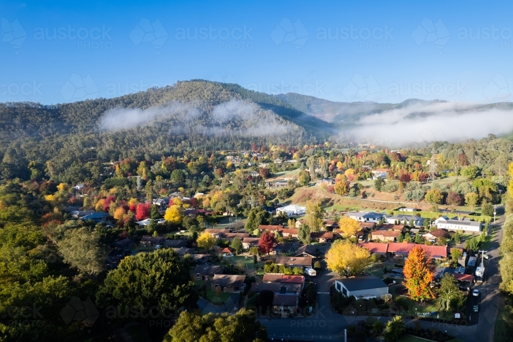 Looking over a town filled with autumn trees on a blue sky day - Australian Stock Image