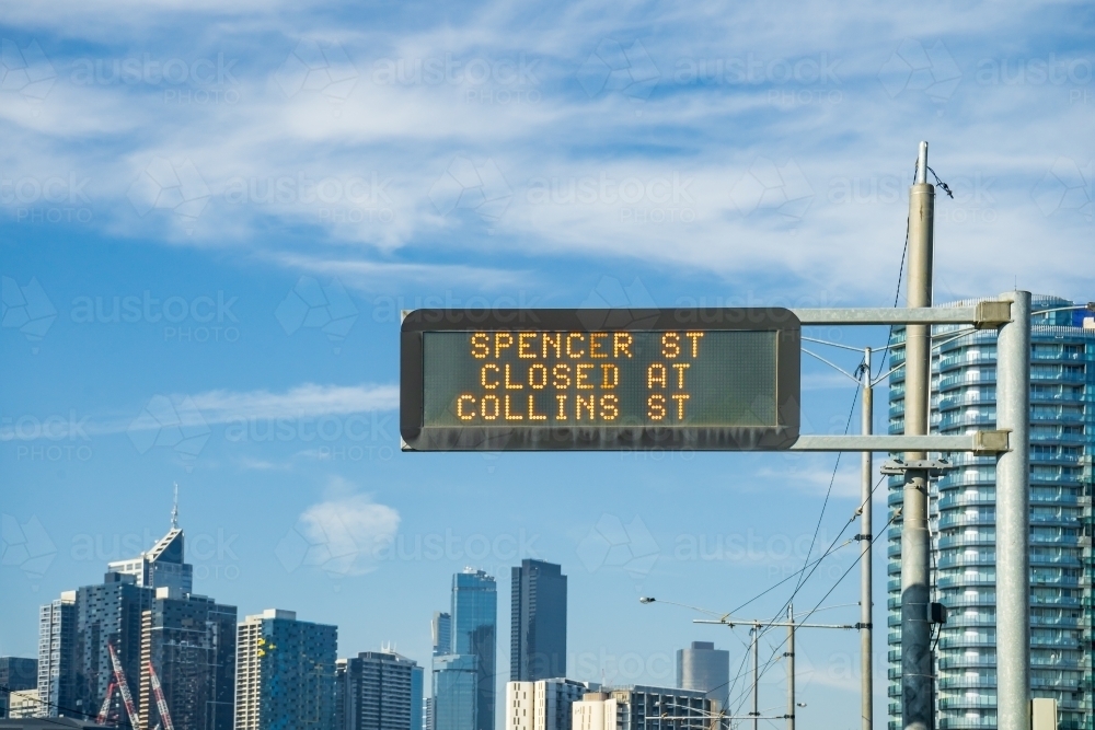 Looking up an overhead traffic sign set against a city skyline - Australian Stock Image