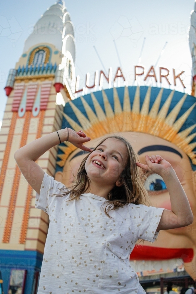 Low angle shot of young girl in front of Luna Park - Australian Stock Image