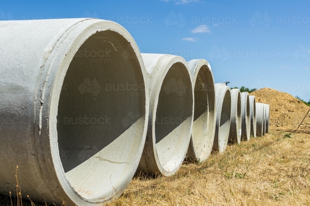 Low angle view of a row of large cement pipes - Australian Stock Image