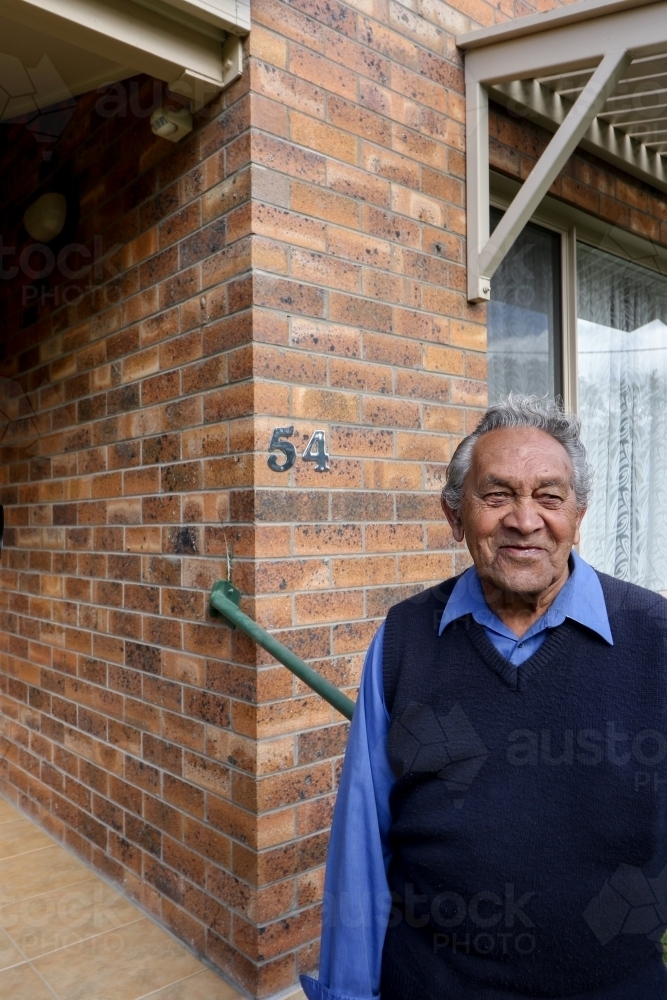 Male Aboriginal elder standing in front of his home - Australian Stock Image