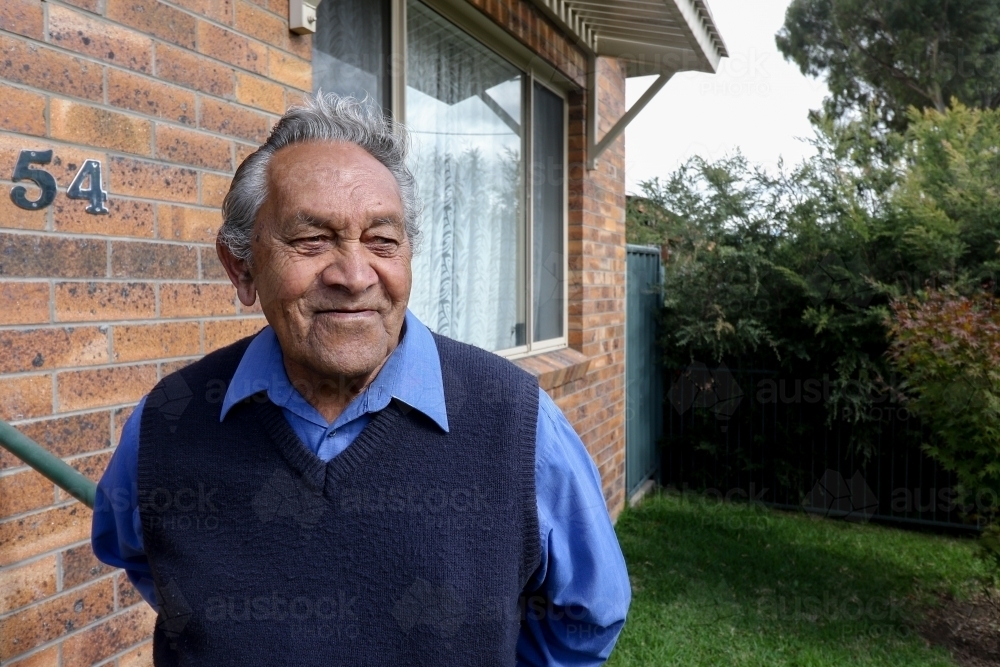 Male Aboriginal elder standing in front of his home - Australian Stock Image