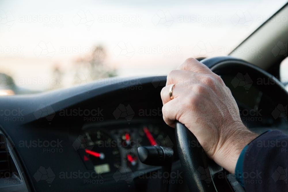 Male driver driving car with one hand on steering wheel - Australian Stock Image