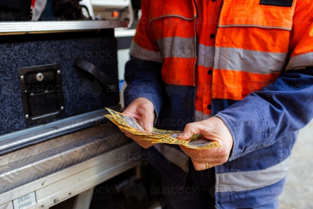 Male tradie counting cash payment for job paid in cash - Australian Stock Image