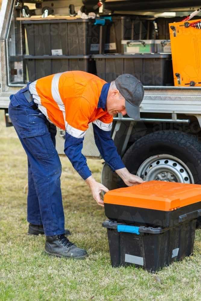 male tradie opening box of tools beside ute - Australian Stock Image