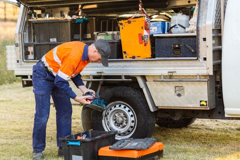 male tradie opening box of tools beside ute - Australian Stock Image