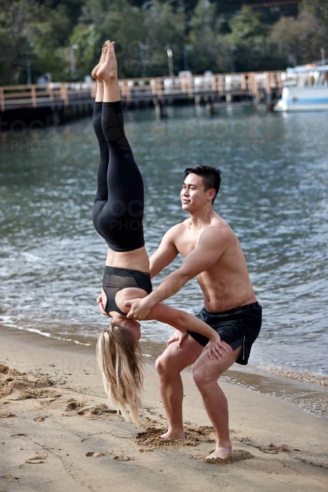 Man and woman practising acrobatics on beach - Australian Stock Image