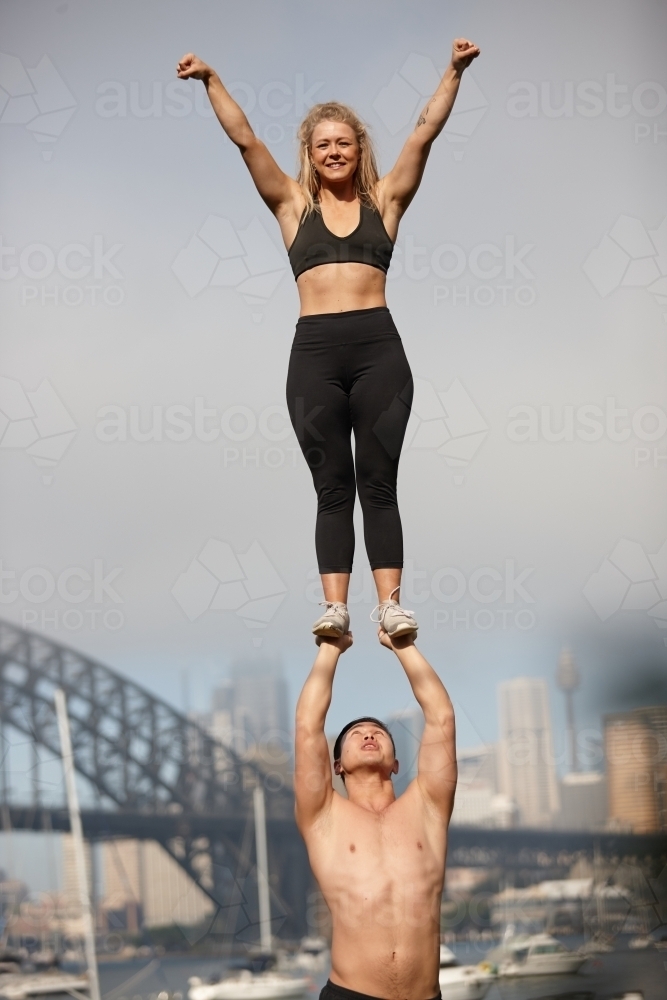 Man and woman practising acrobatics with harbour bridge in background - Australian Stock Image